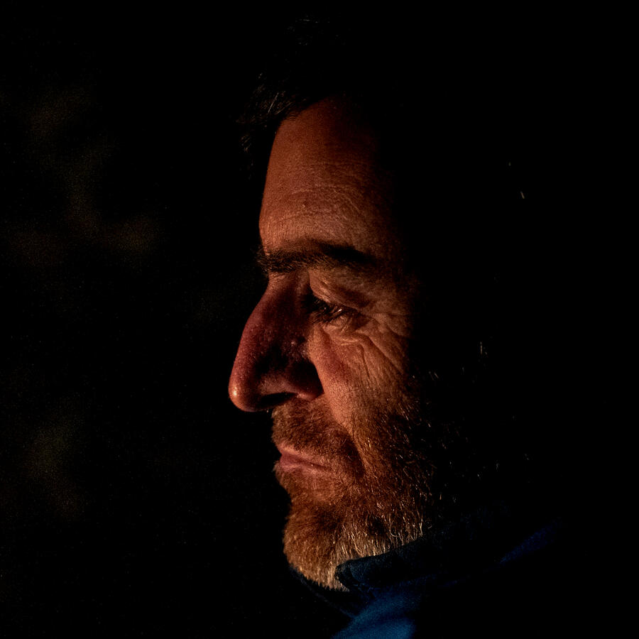 Mormon man yearning for deeper spirituality and purpose. Image of a man staring into a fire, conveying the process of a faith transition or faith expansion.